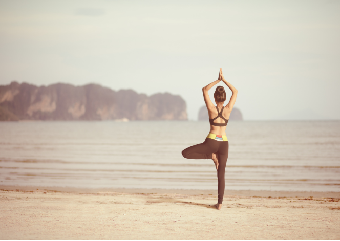 A woman doing yoga on the beach by the ocean